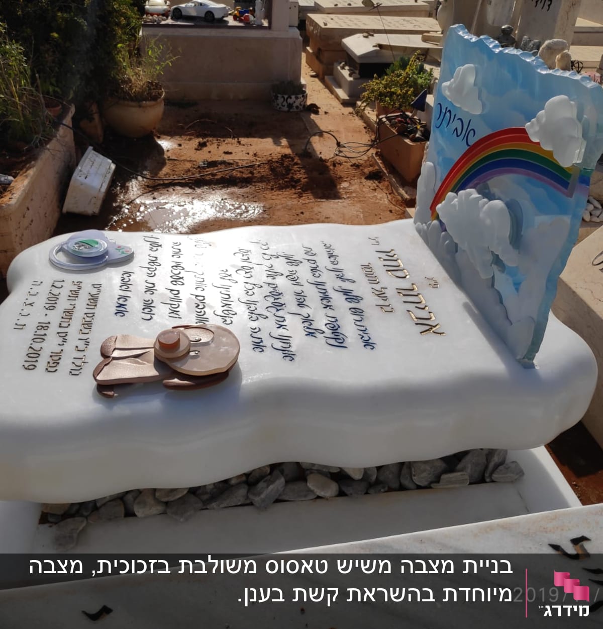 מצבה עם כיתוב בעברית וקשת בענן